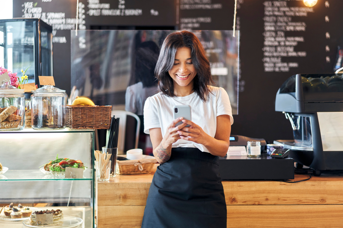 A shop owner uses the DirecTV for Business app on her smart phone.