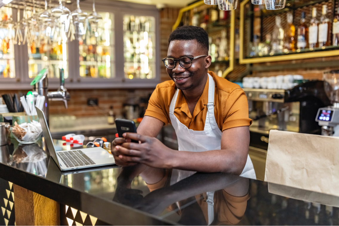 A shop owner works on their marketing online with their smart phone.