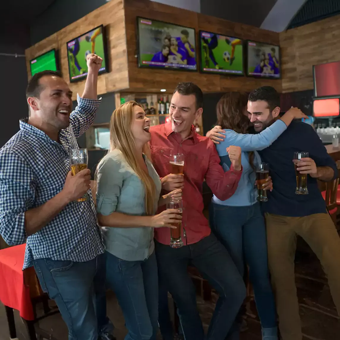 Excited friends celebrate while watching a soccer game on tv.