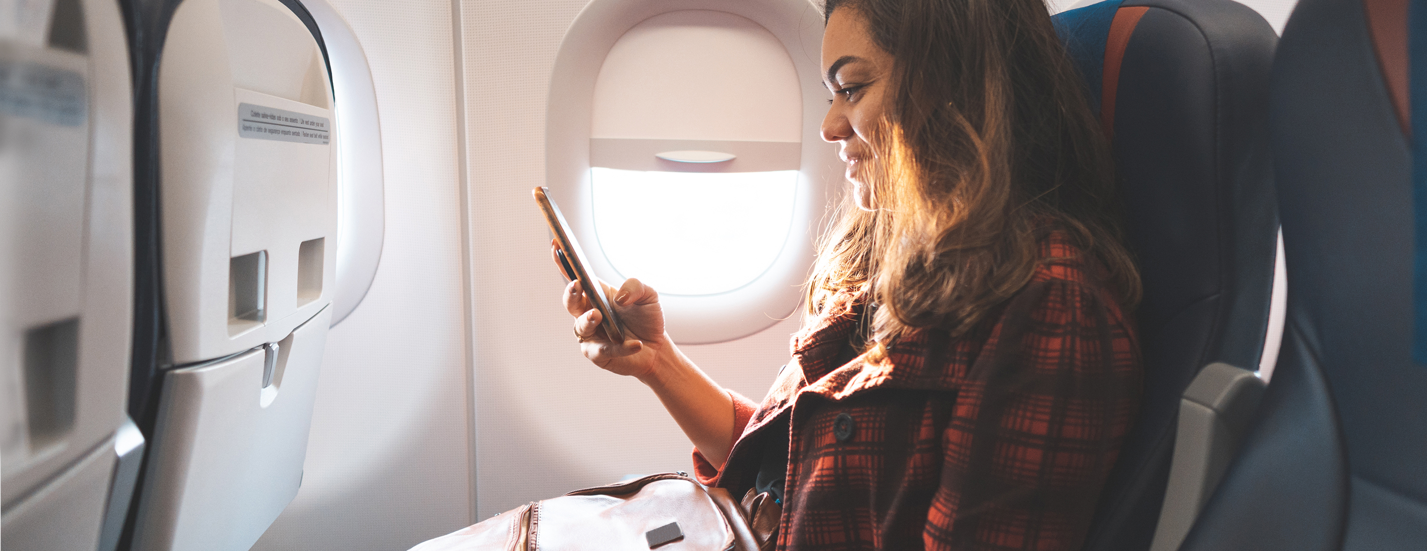 Woman watching movie on her phone on an airplane.