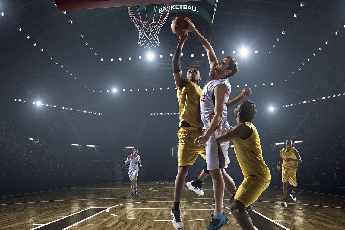 Basketball player getting blocked as he tries to dunk the ball