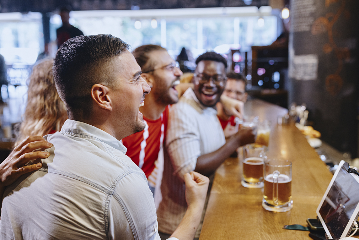 friends sitting at the bar cheering on their sports team.