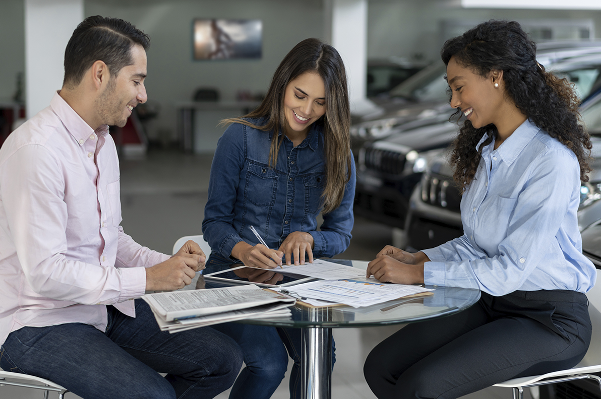 Couple signing contract on a new car at the dealership