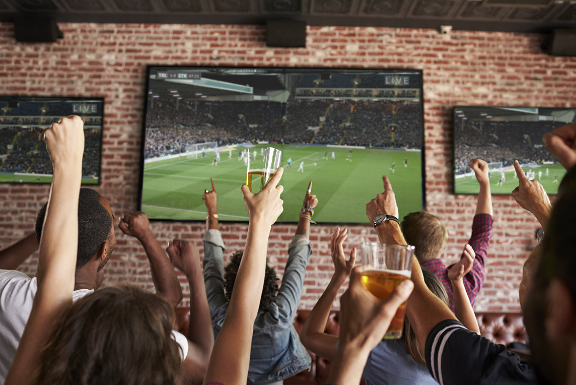friends cheering for sports team on TV at the bar