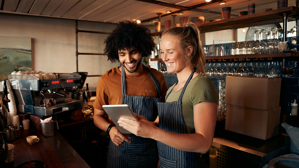 Two coffee shop owners laugh while working.
